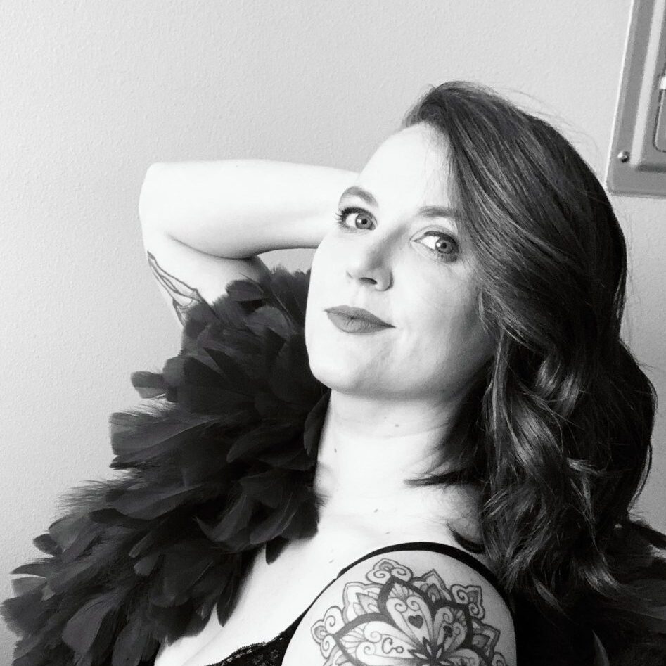 Black-and-white portrait of a woman with styled hair and a tattooed arm.