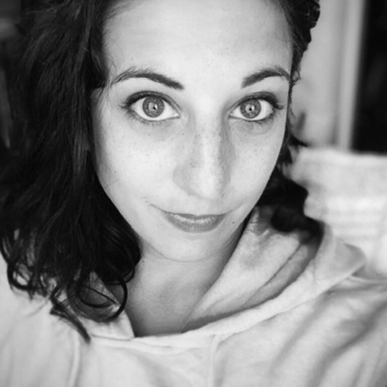 Black and white close-up portrait of a woman with curly hair and expressive eyes.